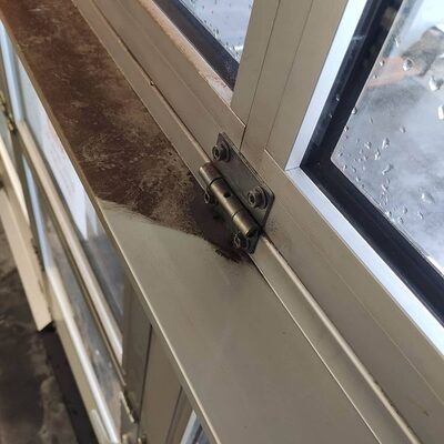 Fensterrahmen mit Scharnier, ein Teil bereits gereinigt, der übrige Bereich noch verschmutzt