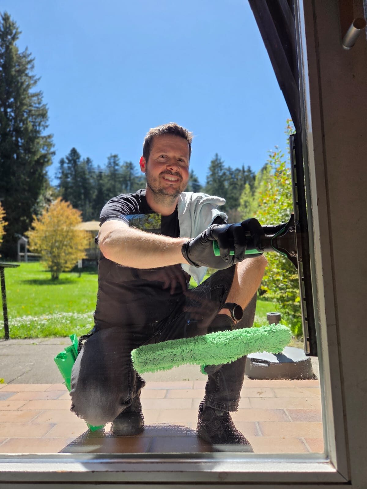 Mitarbeiter der Clean Lady reinigt eine Fensterscheibe mit Abzieher und Einwascher