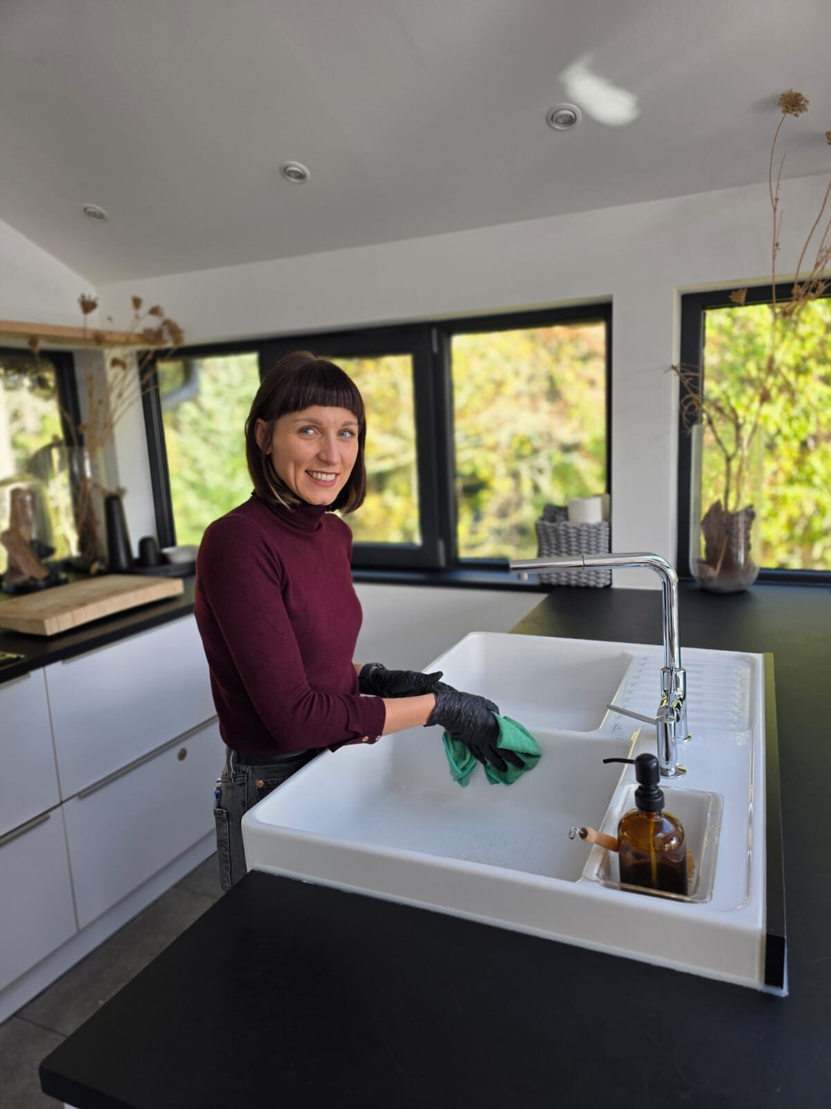 Mitarbeiterin der Clean Lady reinigt ein Spülbecken in einer Privatküche